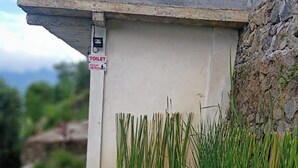 Een betonnen constructie met een pictogram voor een toilet, een witte emmer en een metalen kom.