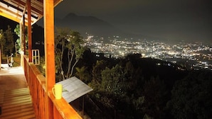 Une terrasse en bois offrant une vue sur la ville la nuit.