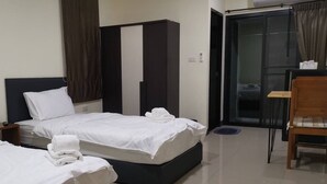 Une chambre d’hôtel avec deux lits, une armoire, une chaise et une porte-fenêtre coulissante donnant sur le balcon.