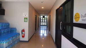 Un couloir d’hôtel équipé d’un extincteur, d’un système de stockage d’eau et d’un panneau indiquant un code QR pour l’enregistrement.