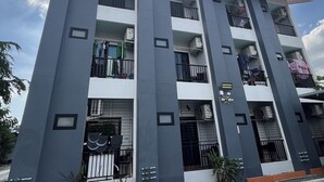 Un immeuble à plusieurs étages doté de balcons, de climatiseurs et d’une entrée sécurisée par un portail.