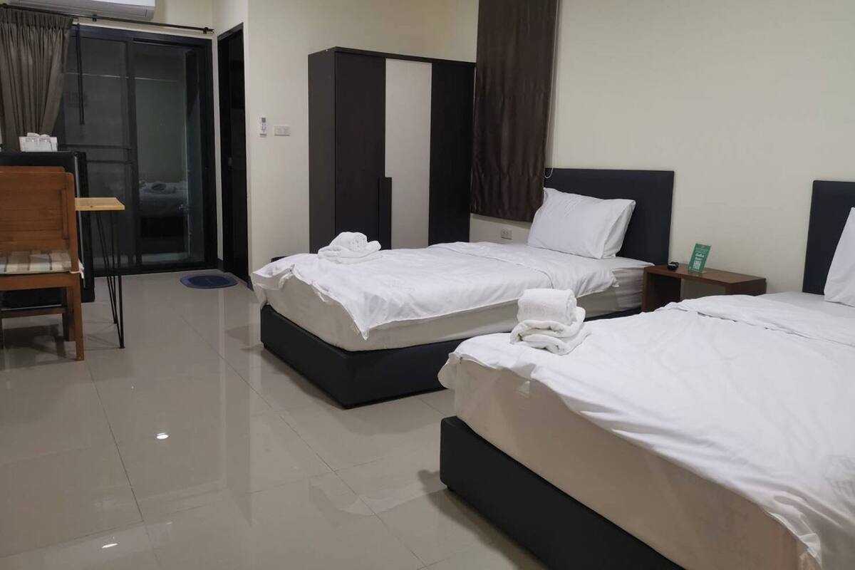 Een hotelkamer met twee bedden, een kledingkast, een bureau en een stoel.