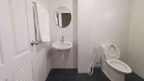 Une petite salle de bain propre, équipée de toilettes, d’un lavabo et d’un miroir.