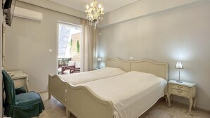 Un dormitorio con dos camas, un candelabro, una ventana con cortinas, una silla, una mesita de noche y una lámpara.