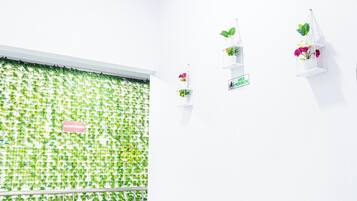 A room with a green leafy wall, white shelves with plants, and a sign reading "MEREKROKON".