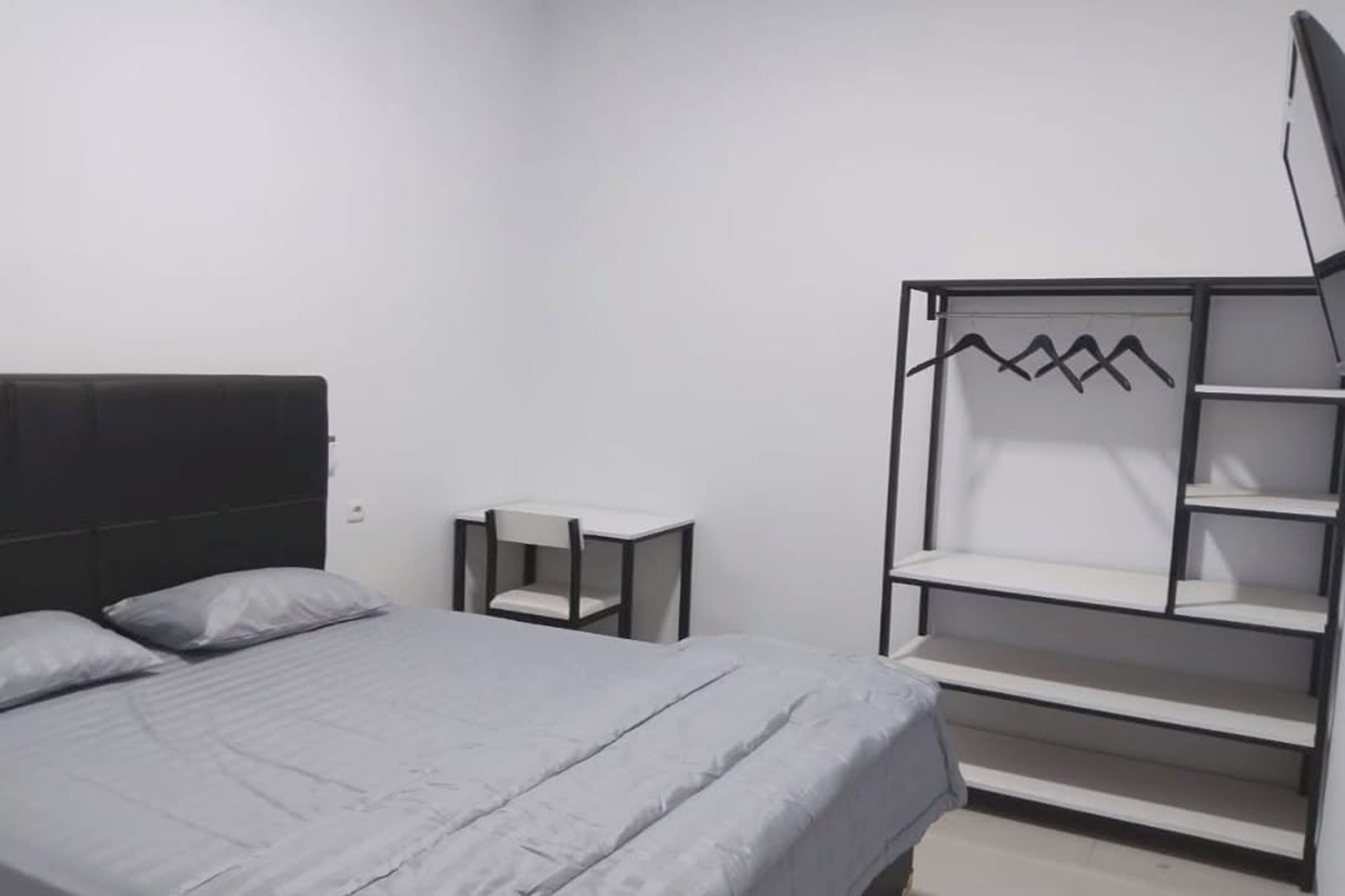 Une chambre à coucher comprenant un lit, une petite table et une armoire intégrée avec des étagères.