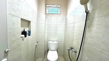 Un baño pequeño con azulejos, un inodoro, una ducha y una ventana.