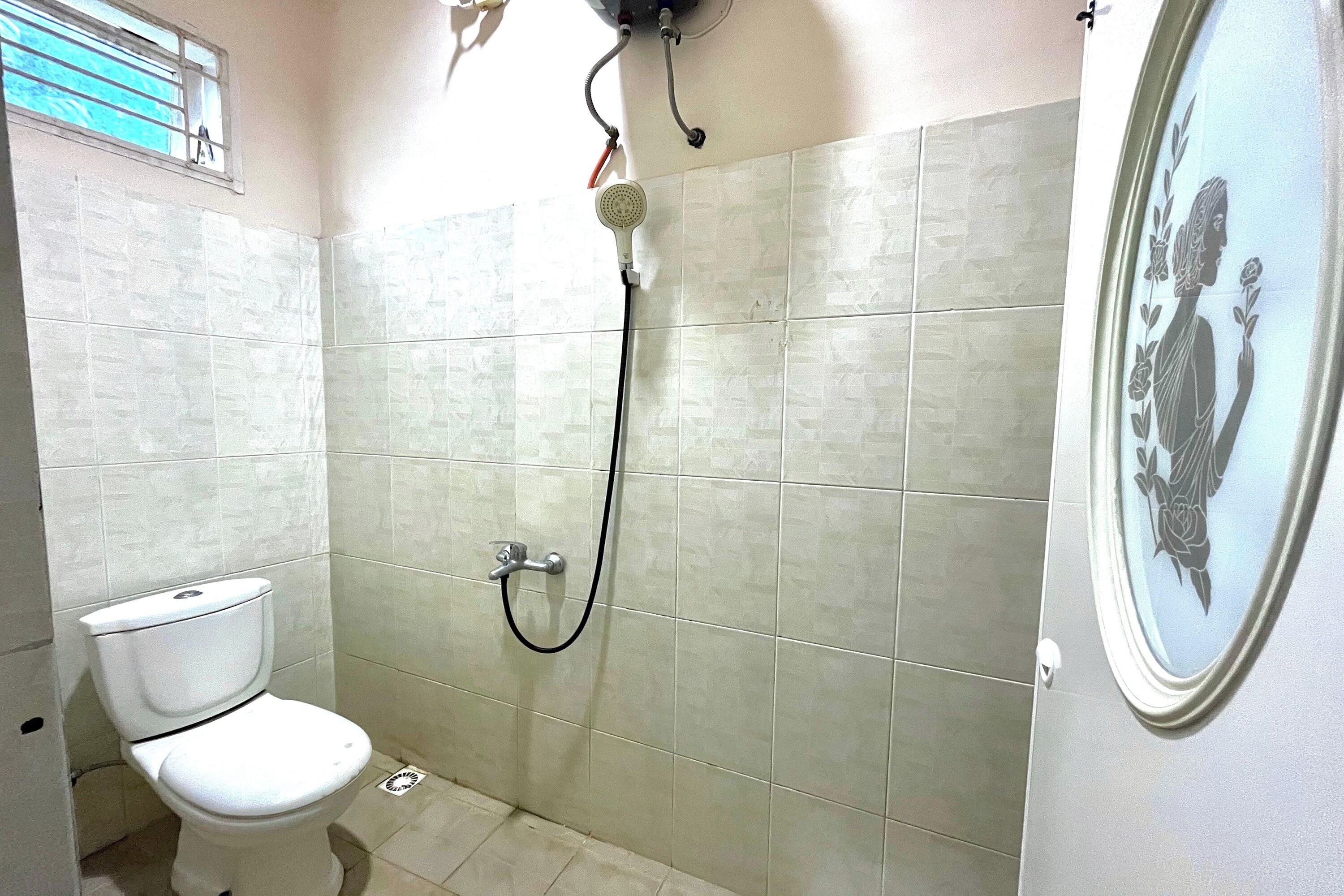 A small bathroom with a toilet, a shower, and a wall-mounted sink.