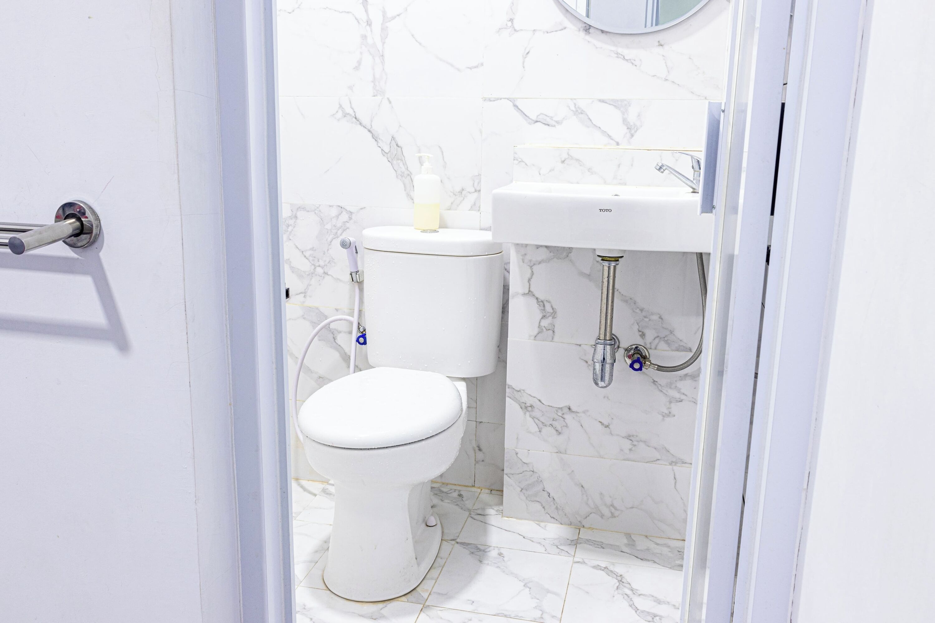 Un baño con inodoro, lavabo y paredes con azulejos de mármol.