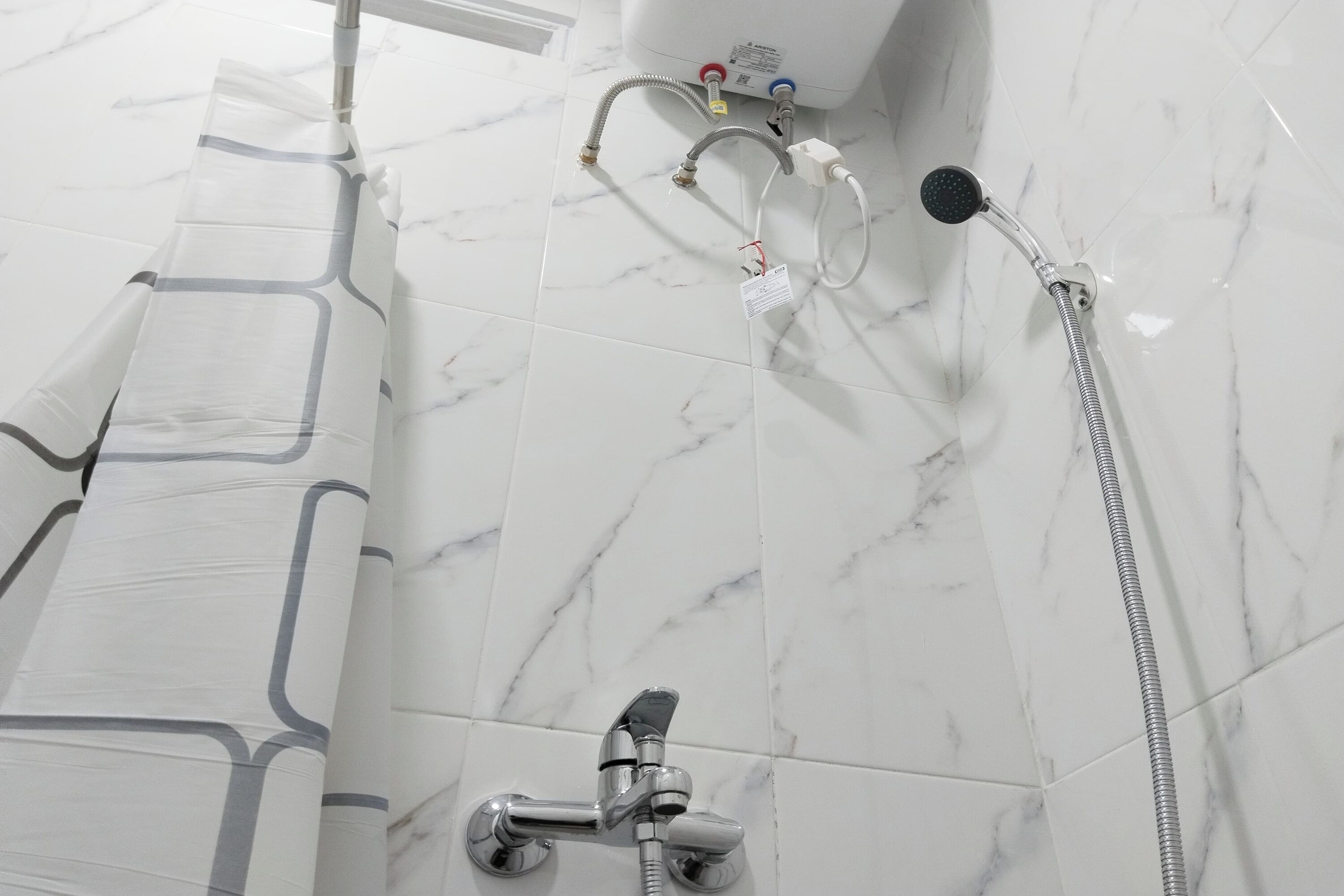 Une salle de bain équipée d’une douche, d’un pommeau de douche amovible et d’un robinet mural.