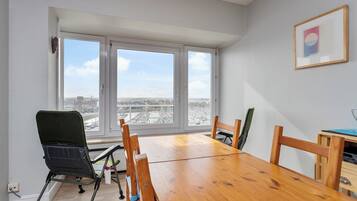 Une pièce avec une grande fenêtre, une table à manger en bois et une chaise.
