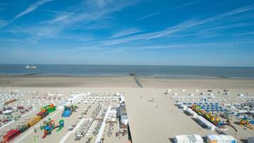 Une plage dotée de nombreux parasols et de chaises longues, d’un toboggan aquatique et d’une tour de surveillance pour les sauveteurs.
