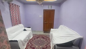 A room with two beds covered with white sheets, a red patterned rug, a ceiling fan, and a chandelier. - duplexhotel (Hyderabad)