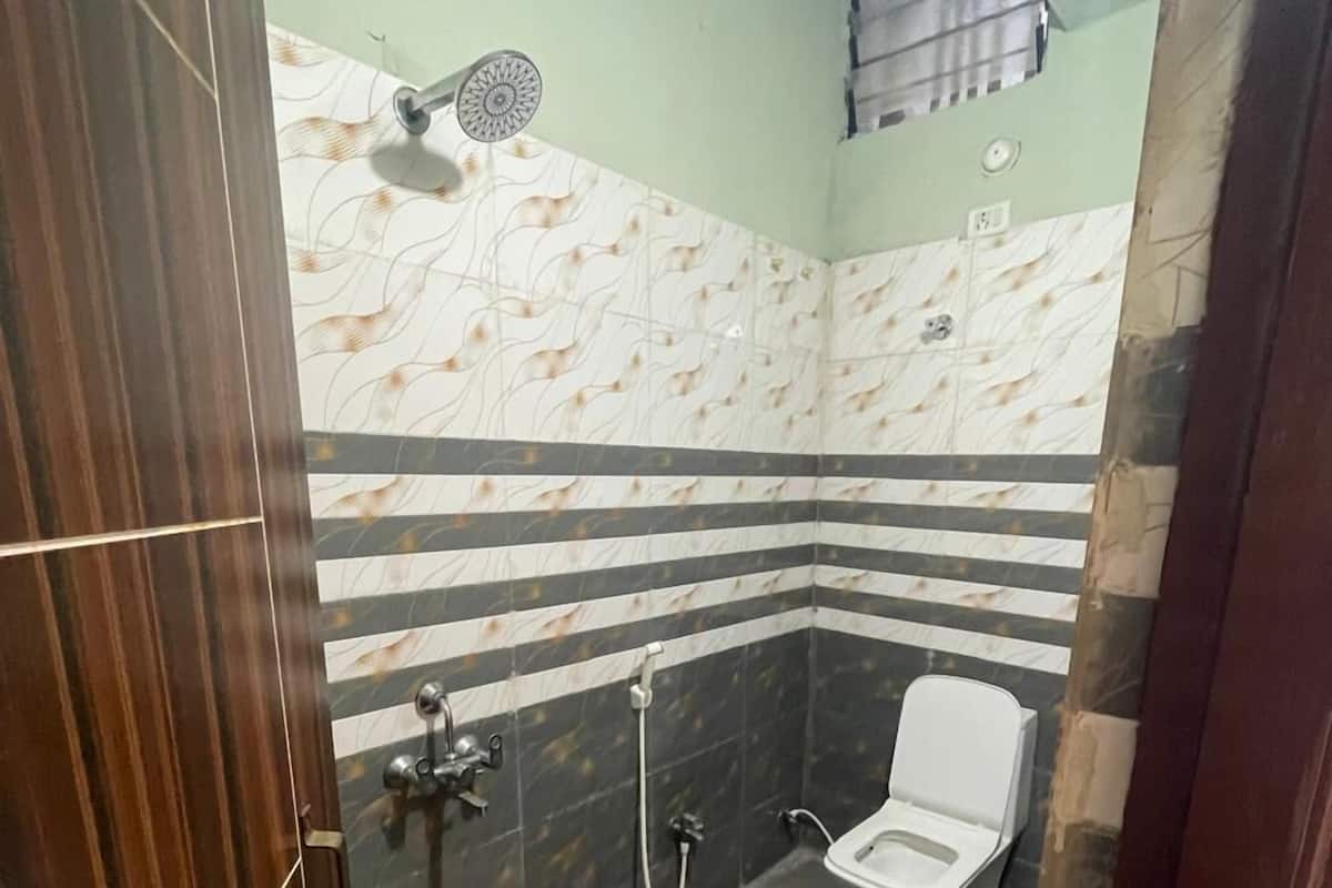 Ein Badezimmer mit Toilette, Dusche und einem roten Eimer auf dem Boden.