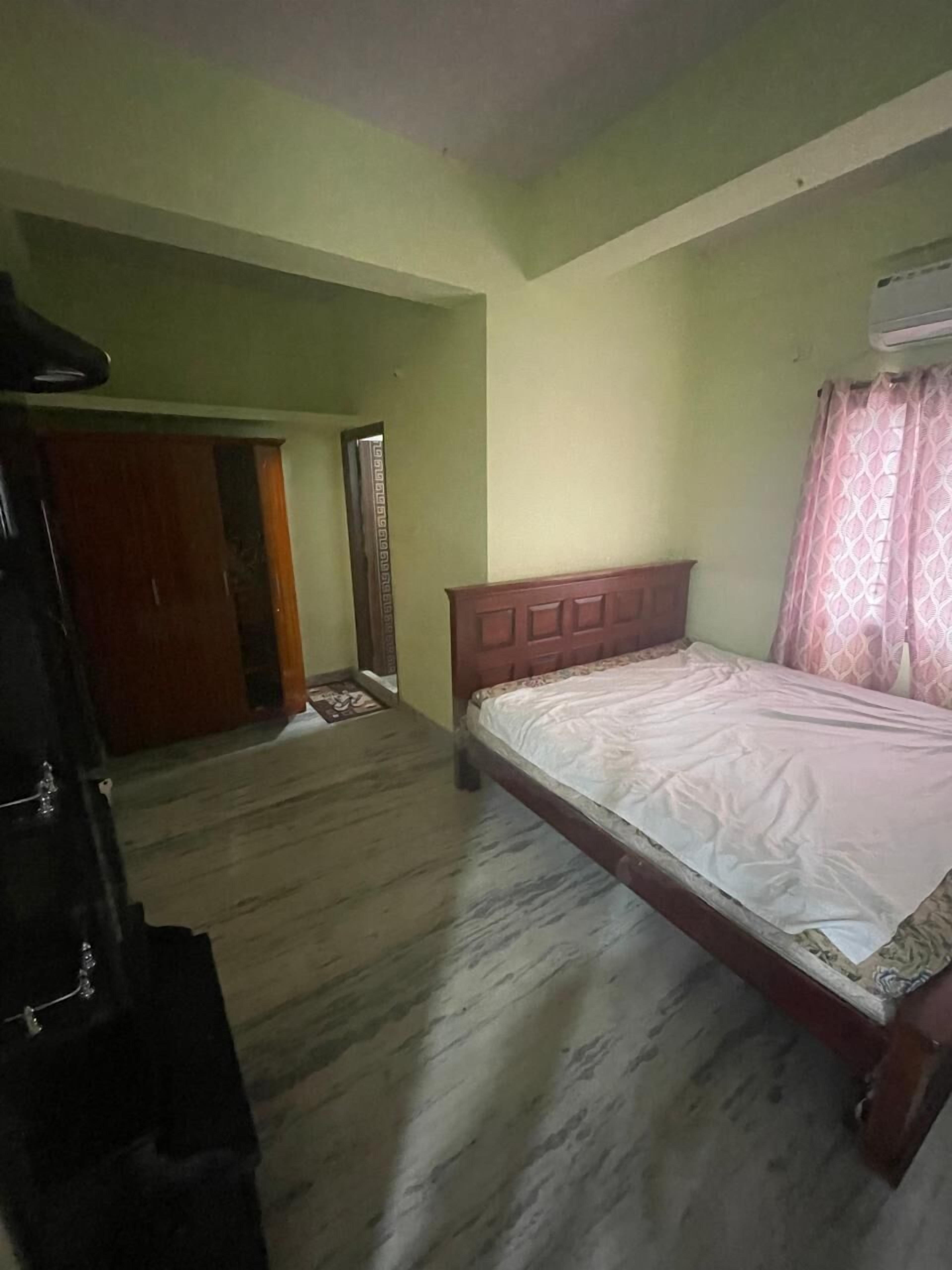 A bedroom with a wooden bed, a wardrobe, and a door leading to another room.