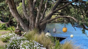 Un entorno tranquilo junto al río, con un árbol grande, flores blancas y tres boyas flotantes.