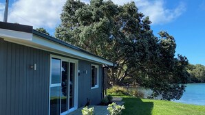 Una casa moderna con un porche, un árbol grande y vistas al lago.