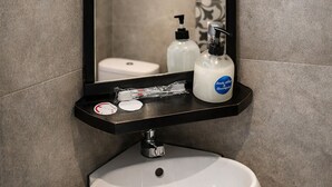 Une salle de bain avec un lavabo blanc, un miroir et des articles de toilette posés sur le comptoir.