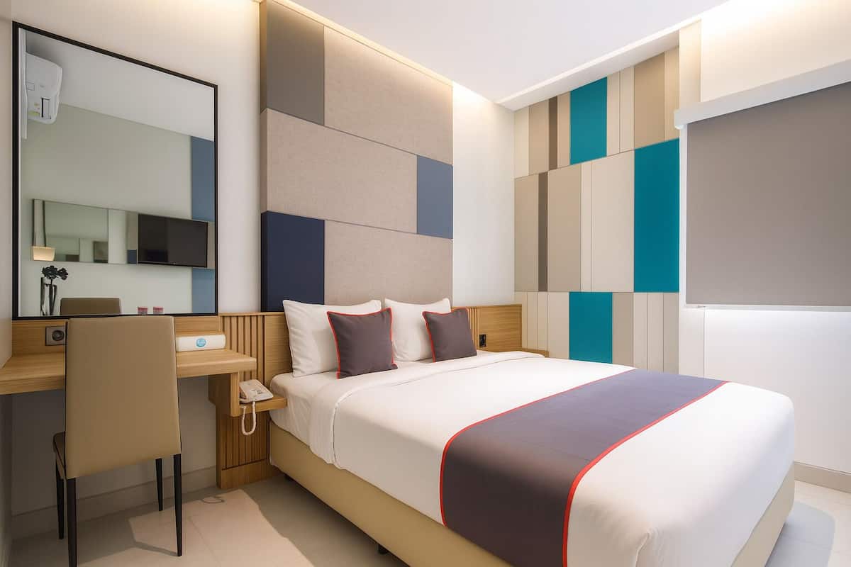 A modern hotel room with a bed, a desk, and a chair.