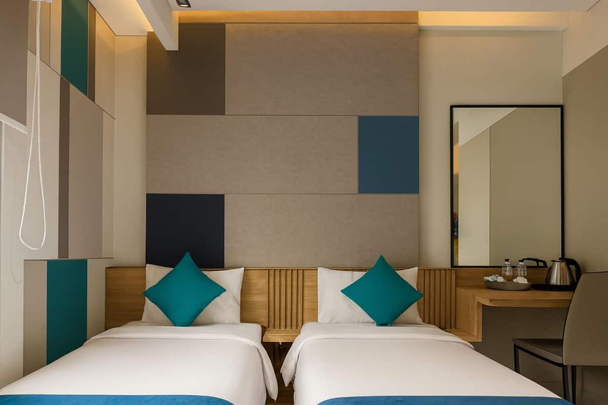 A hotel room with two beds, a desk, a chair, a mirror, and a telephone.