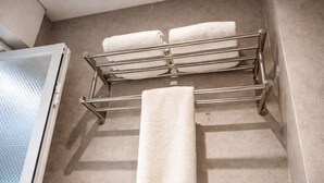 Une salle de bain avec un porte-serviettes sur lequel sont pliées trois serviettes, et une serviette supplémentaire suspendue en dessous.