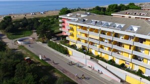 Ett hotell med flera våningar och en gul fasad, beläget nära en strand med fri utsikt över havet.