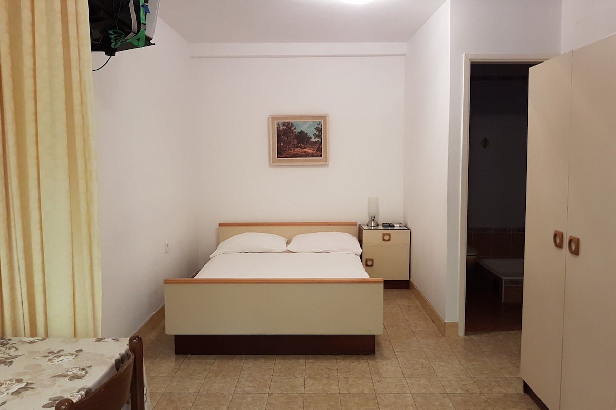 Une chambre à coucher avec un lit, une table de chevet, un tableau, une armoire et une chaise.