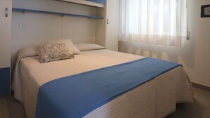 Un dormitorio con una cama, un edredón azul y un cojín con diseño floral.