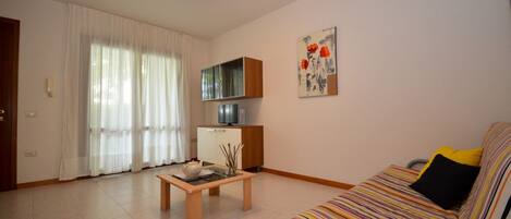 A living room with a sofa, a coffee table, a cabinet, and a painting on the wall.