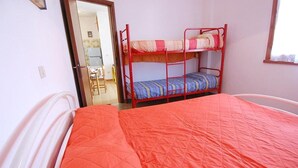 A room with a bunk bed, a single bed, and a door leading to another room.
