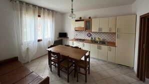 Une cuisine de taille réduite comprenant une table et des chaises, un téléviseur et les appareils électroménagers de base.