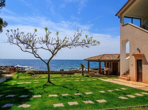 A coastal property with a stone pathway leading to a gazebo, a tree, and a view of the sea. - Beachfront Escape in Rovinj (Rovinj)