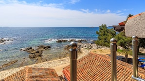 A coastal view with a clear sky, rocky shoreline, and terracotta-tiled buildings. - Beachfront Escape in Rovinj (Rovinj)
