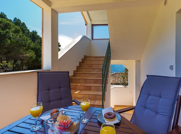 A balcony with a table set for breakfast, a staircase, and a view of the sea. - Beachfront Escape in Rovinj (Rovinj)