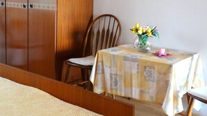 A room with a bed, a wooden wardrobe, a dining table with a vase of flowers, and a chair. - Comfortable Crikvenica Studio Apartments With Balcony (Crikvenica)