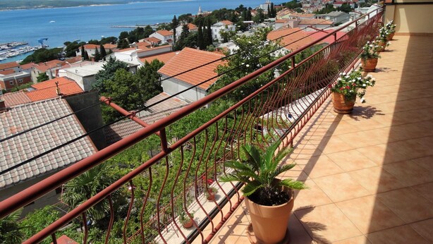 A balcony with a view of a coastal town, potted plants, and a satellite dish. - Comfortable Crikvenica Studio Apartments With Balcony (Crikvenica)