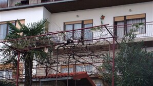 A multi-story building with a stone facade, balconies, and a small garden area with potted plants. - Comfortable Crikvenica Studio Apartments With Balcony (Crikvenica)