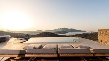 A rooftop pool area with lounge chairs and a view of the surrounding landscape.