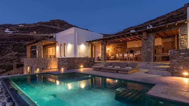 Une villa moderne dotée d’une piscine, de murs en pierre et d’un espace salon extérieur.
