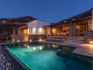 A modern villa with a swimming pool, stone walls, and outdoor seating. - Charming Villa Near Ftelia Beach (Doxato)