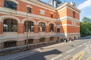 A historic building with red brick facade, large arched windows, and classical architectural details. - Charming Studio- 2P- Jardin des Plantes/austerlitz (Paris)