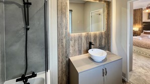 A bathroom with a bathtub, a sink with a mirror, and a shower area.