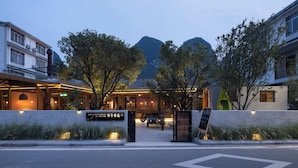 A bar and restaurant with a mountain backdrop, a motorcycle parked in front, and a signboard. - See You in the mountains (Guilin)