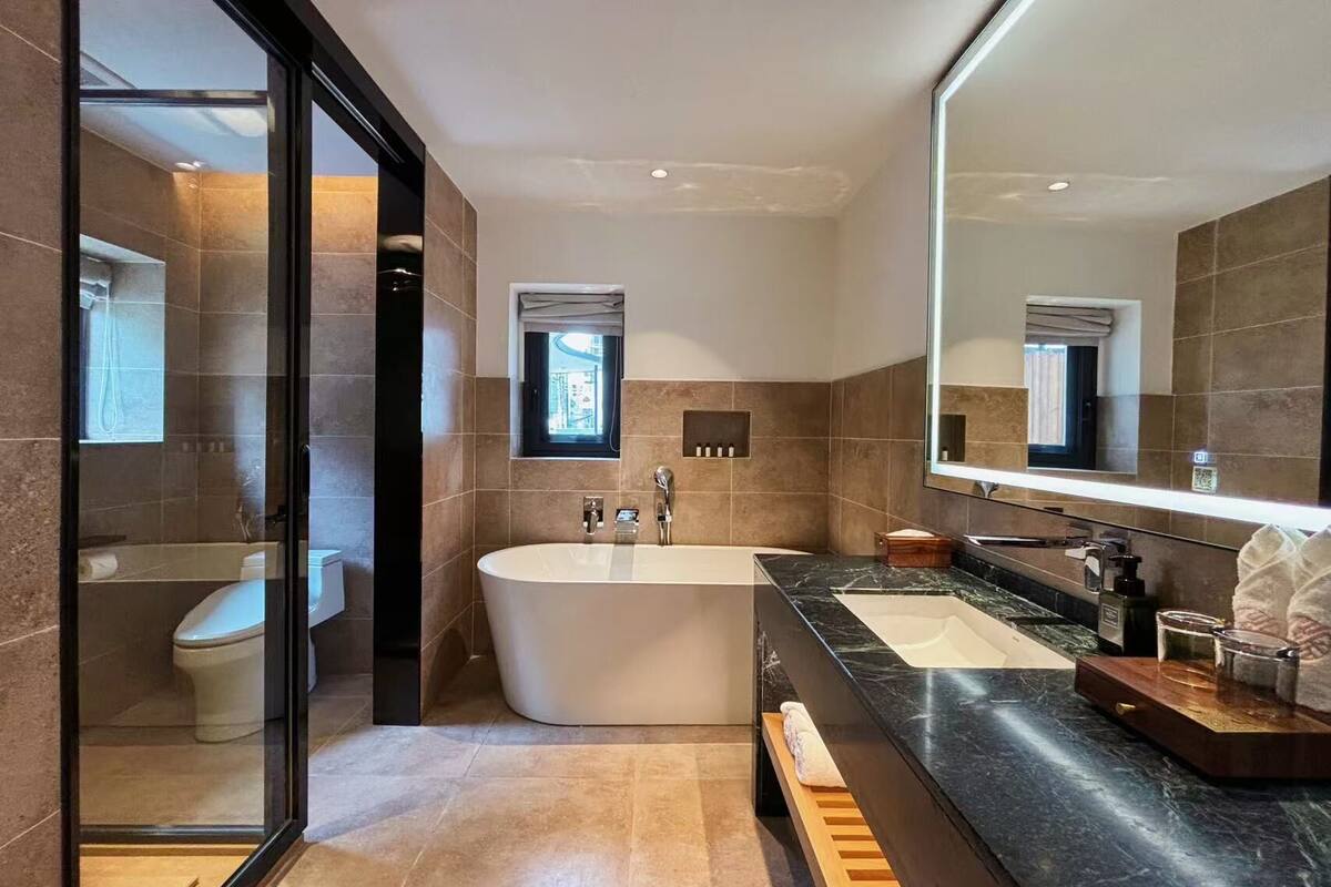 A modern bathroom with a freestanding bathtub, a vanity with a large mirror, and a glass-enclosed shower area.