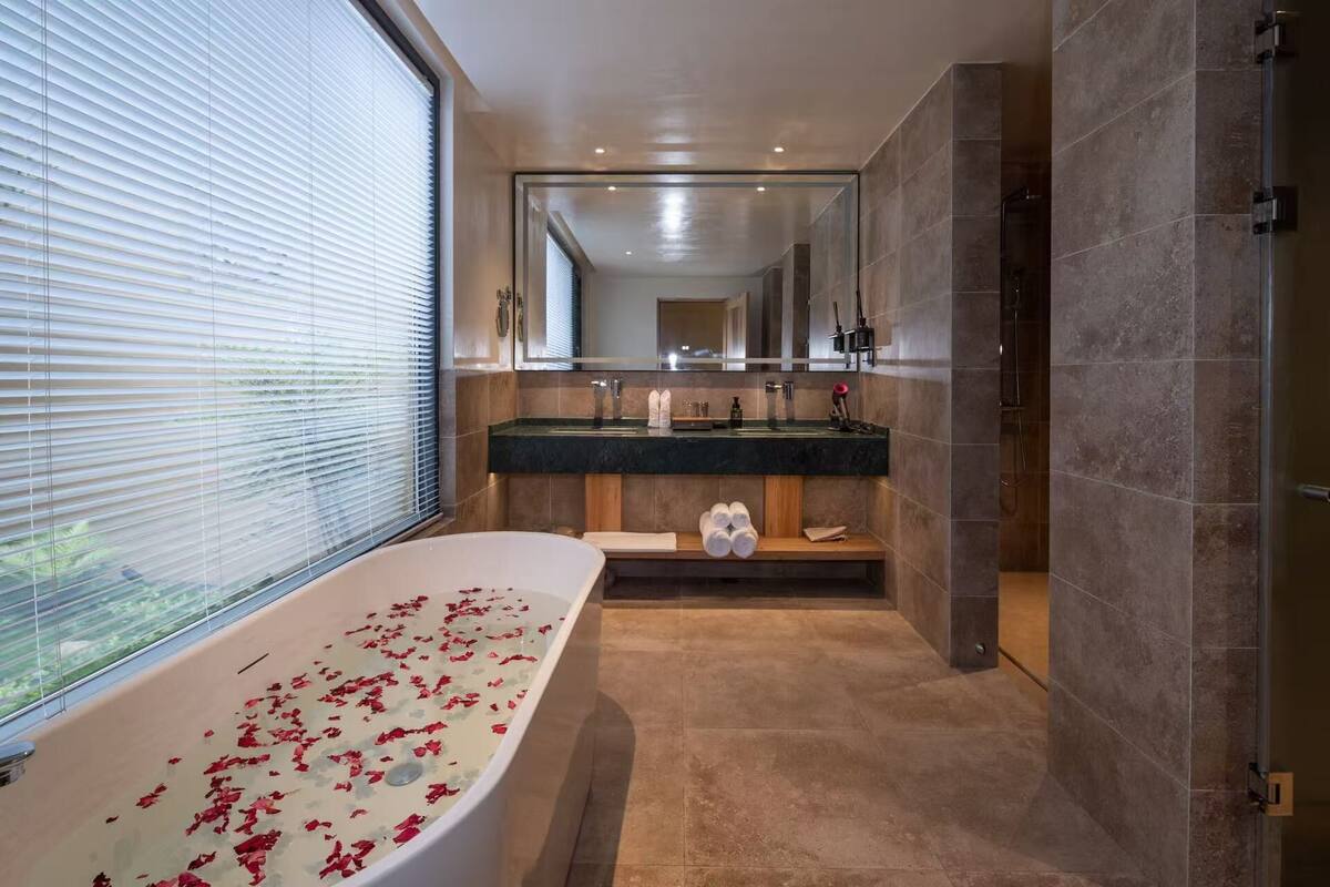 A modern bathroom with a freestanding bathtub, a large mirror, and a walk-in shower.