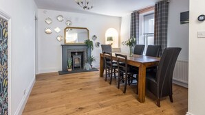 A dining area with a wooden table and chairs, a fireplace, and a chandelier.
