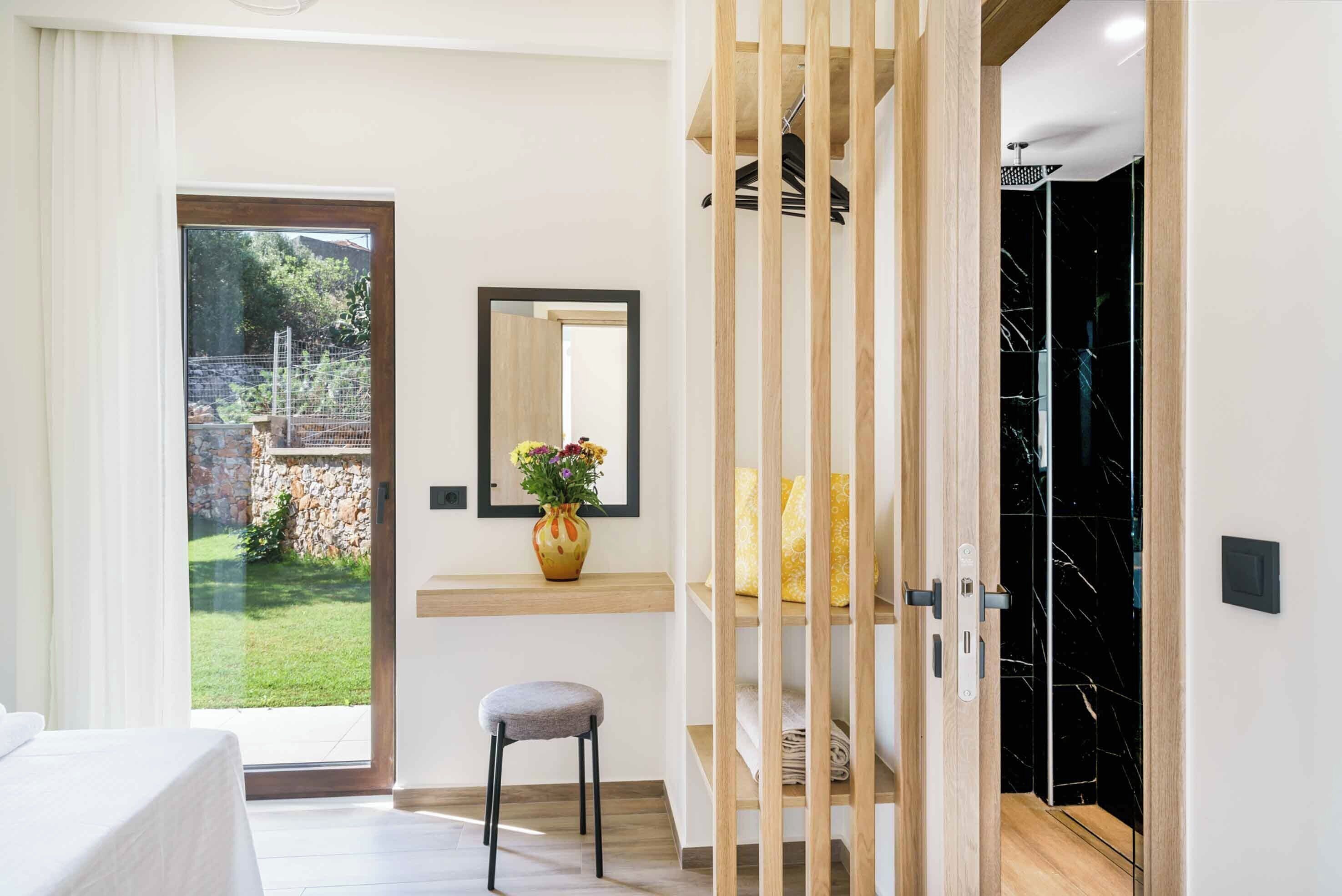 A modern bathroom with a shower, a wooden stool, and a mirror on the wall.