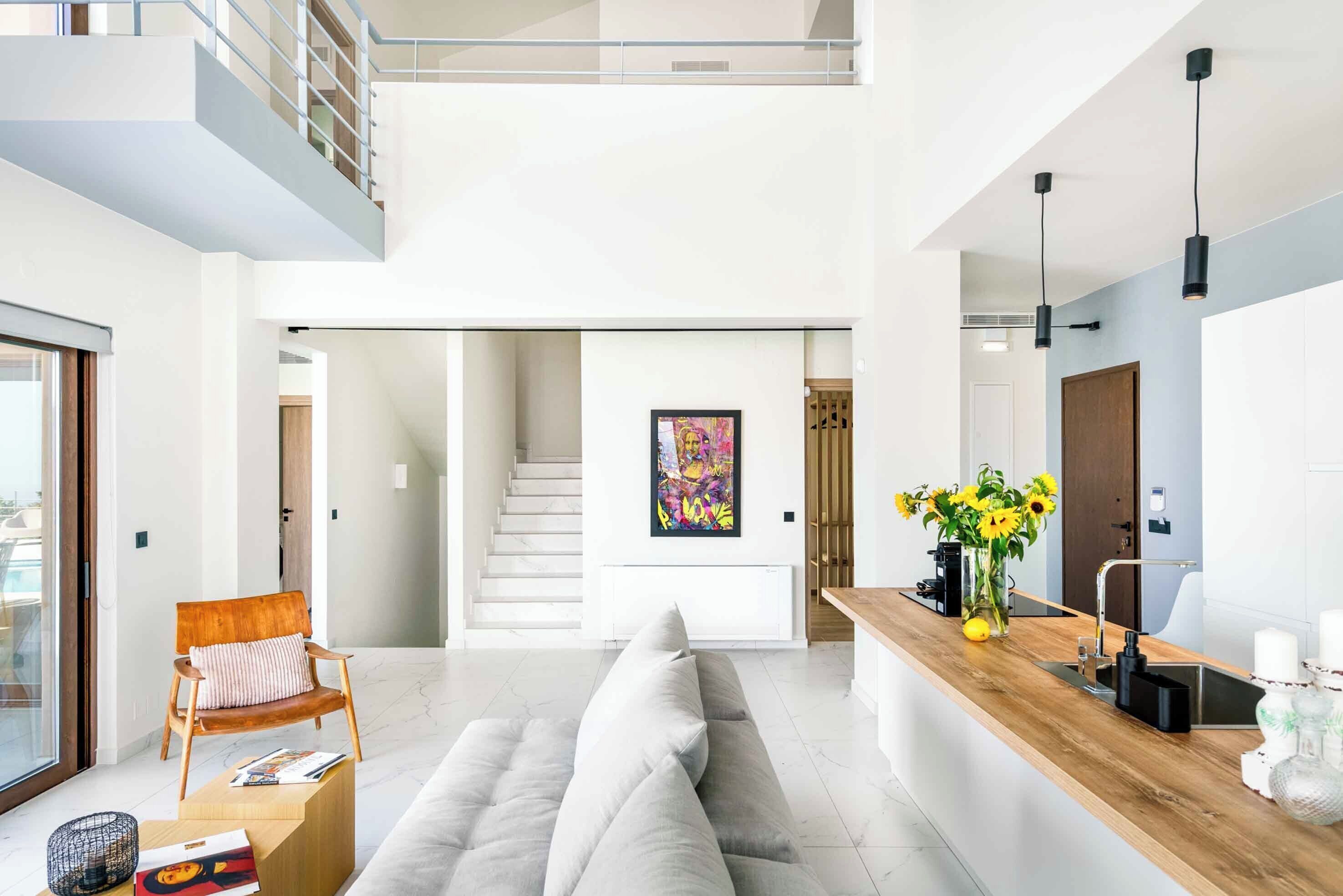 A modern interior with a living area, a wooden reception desk, and a staircase leading to an upper level.