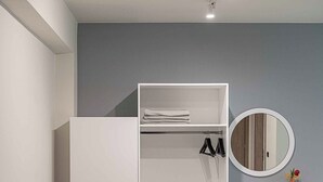 A modern room with a grey sofa, a white wardrobe, a round mirror, and a small desk with a vase. - Olimpia Villas (Apokoronas)