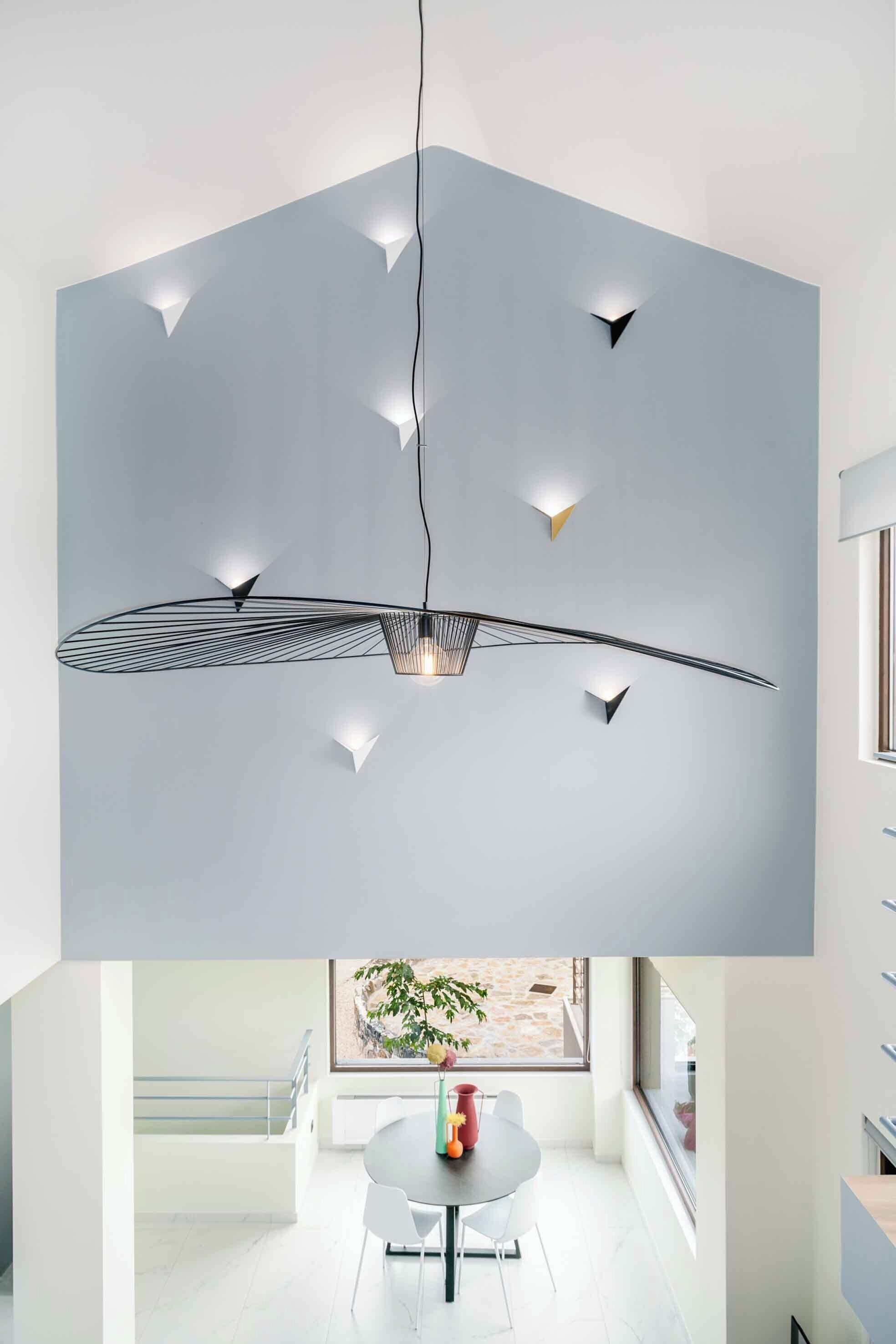 A modern interior with a geometric pendant light fixture and a dining area with a round table and chairs.